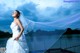 A woman in a wedding dress standing on a bridge.