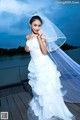 A woman in a wedding dress standing on a dock.