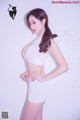 A woman in a white top and shorts posing for a picture.